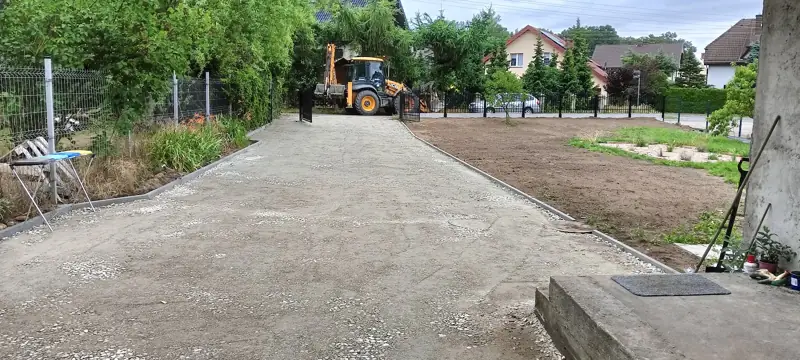 Utwardzony plac przed domem, w tle koparko-ładowarka JCB